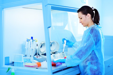 A young female scientist works in a sterile genetic or bacteriological laboratory with a dispenser...