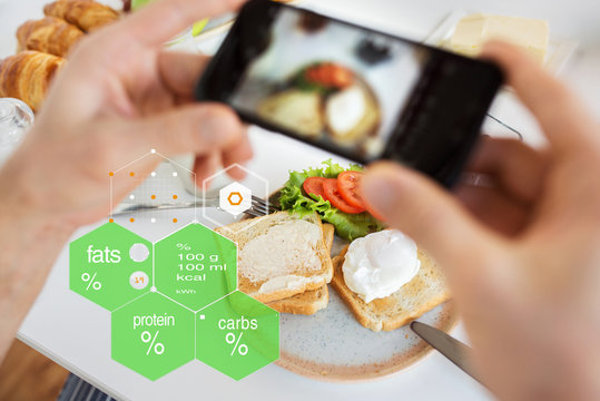 food, eating and technology concept - hands with toasts and vegetables on smartphone screen over nutritional value chart
