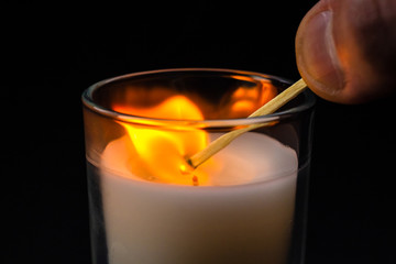 A match in hand ignites a candle in a glass jar. Sadness, remembrance and condolence concept
