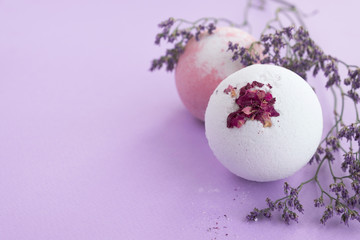 Bath bombs and branch flowers on purple background. Natural cosmetics and home spa concept. Provence style. Close up, copy space