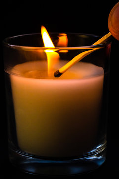 A match in hand ignites a candle in a glass jar. Sadness, remembrance and condolence concept