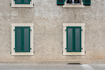 Facade of a stone house with green shutters. Swiss - French border