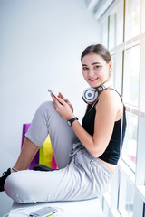 Fototapeta na wymiar happy young attractive Caucasian woman using smartphone or cellphone connecting with earphone to listening music at coffee or coffe shop in the morning
