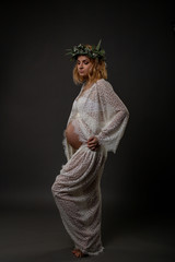 vertical portrait of a beautiful pregnant woman with a wreath on her head