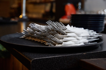 forks wrapped in a napkin on a tray in a dark cafe