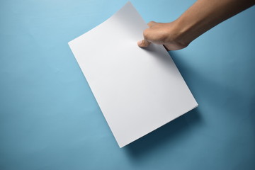 Mockup Hand Holding Blank White Paper isolated on Blue clear background, empty Paper for message or...