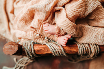 A newborn cute baby sleeping in a vintage wooden cradle with open foot and toes. 