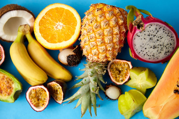 food, summer and healthy eating concept - different exotic fruits on blue background