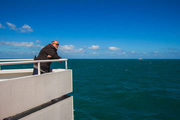Sea voyage in Dover Strait, mature man looking at sea from ship, horizon view.