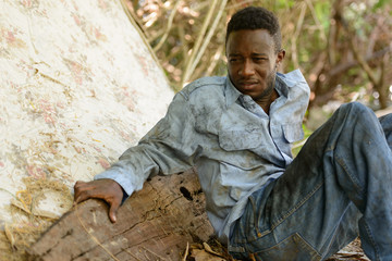 Obraz premium Sad young homeless African man sitting in the streets