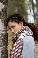 Fototapeta premium Sad woman with dreadlocks hairstyle in the autumn park near birch