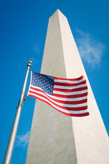 American flag flying outdoors in bright sun at the foot of the Washington Monument in Washington, DC, USA
