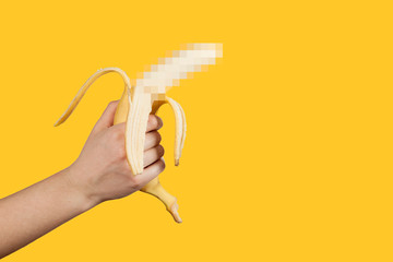 Banana as a symbol of male penis in hand on a yellow background hidden by censorship. Sexual masturbation and orgasm, impotence problem. Self-pleasure concept. - obrazy, fototapety, plakaty