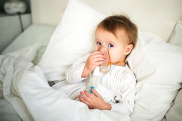 Baby Toddler with nebulizer mask on bed in bedroom