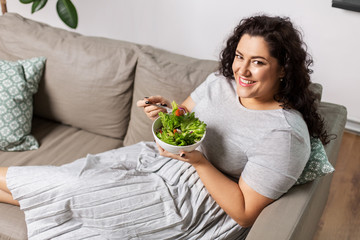 food, diet and people concept - happy smiling young woman eating vegetable salad at home