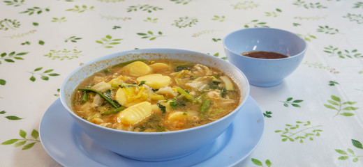 The bowl of hot sukiyaki soup mixed with vegerables with red dipping sauce. 