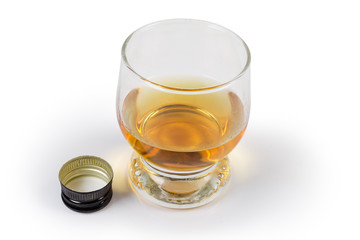 Glass of whisky and screw cap beside on white background