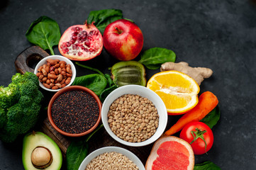 Selection of healthy food:  fruits, seeds, cereals, superfoods, vegetables, leafy vegetables on a stone background. Healthy food for humans. Copy space for your text.
