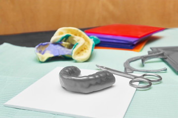 Process of creating custom mouthguard. Silver sports mouthguard with pieces of plastic material and tools.
