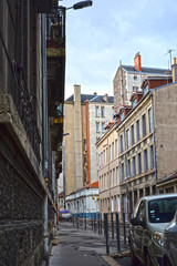 Fototapeta na wymiar Saint-Etienne, France - January 27th 2020 : Old street in the city center, with ancient buildings, showing the steel industrial past of the place. There was mines here in the past.