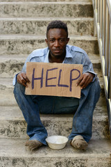 Young homeless African man with cardboard sign asking for help