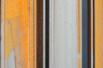 Racks of metal profiles. Metal is stored in an open warehouse. Wet and rusty on the street. Old grunge background made of rusty iron for shooting flatleys on the table