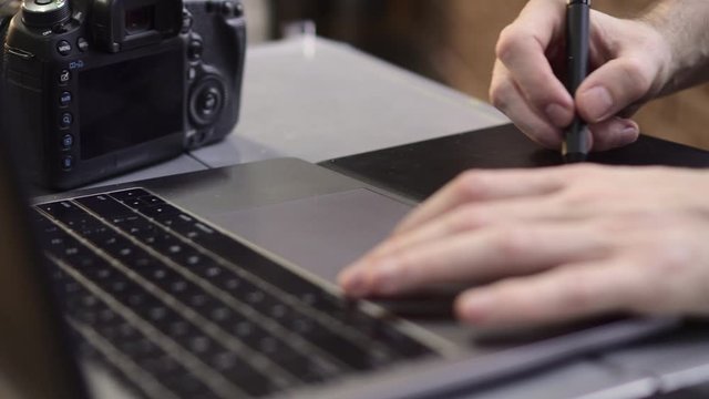 Hands of a male photographer, designer use a graphics tablet. Close up, slider shot.