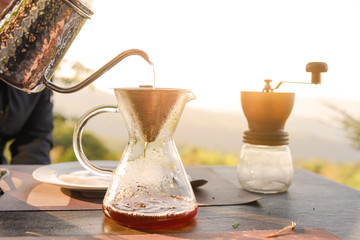 Hand drip coffee making pour over coffee with hot water being poured from a kettle with mountain...