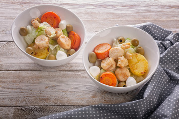 Salad with scallop, vegetables, mozzarella cheese and olives on a wooden rustic table. Delicious seafood