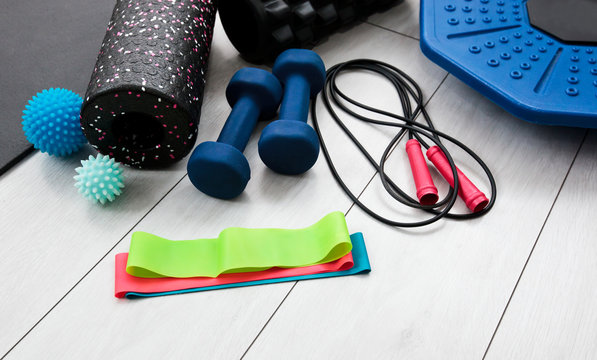 A lot of different fitness and sport accessories and equipment on the wooden floor at home