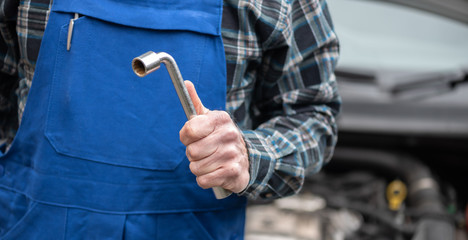 Car mechanic with car engine on background