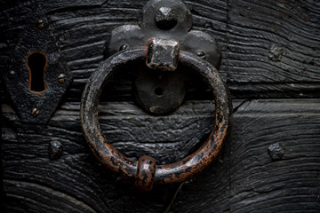 massiver Türklopfer aus Eisen an einer schweren schwarzen Holztür