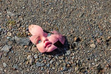 Old broken doll face on ground