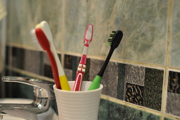 toothbrushes in a white glass on a tile background