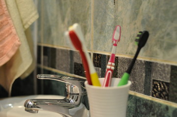 toothbrushes in a white glass on a tile background