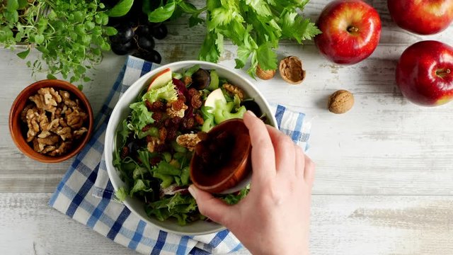 Waldorf Salad. Adding raisins to the salad. Spilling from a small bowl.