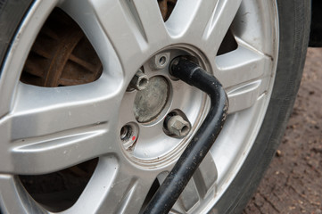 The concept of replacing car tires. Unscrewing the nuts on the wheel with a spanner close-up.