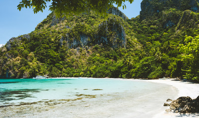 A beautiful empty tropical beach with huge limestone hills and jungle palm trees
