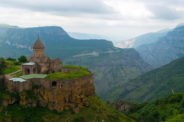 Fototapeta na wymiar Armenia's landmark Tatev Monastery on a cliff of a cliff against the backdrop of high picturesque mountains