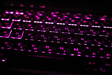 Computer keyboard with Russian and English layout. Backlit by neon light.