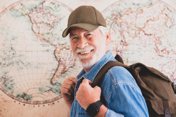 close up and portrait of mature woman wearing trekking clothes with a backpack on his back - portrait of active pensioner looking at the camera smiling with a hemisphere or map at the background