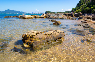 Baia com mar azul esverdeado e pedras de praia tropical< itapema