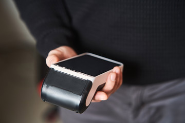 Bank terminal for contactless payment. Acquiring. Young man holds a terminal in his hands.