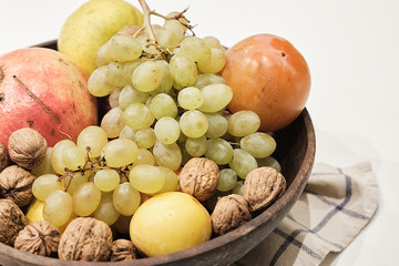 Autumnal fruits in a wooden bowl over a white background