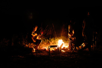Group of people with guitar by the fire