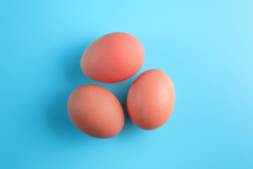 Three red easter eggs on blue surface. Colorful easter eggs decoration. Flat lay, top view. with copy space for text.