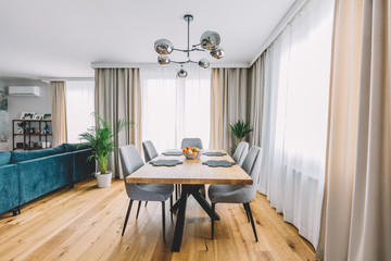 Dining room with wooden table and floor in modern apartment.