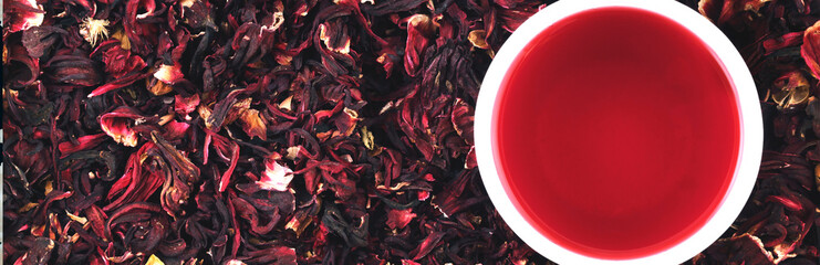 Cup of hibiscus tea on the leaves. Hibiscus background. Panorama. Banner.
