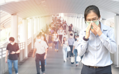 Fototapeta premium Double Exposure image of Asian worker or business woman wearing surgical mask hands covered her mouth while coughing with blurred of crowed,Wuhan coronavirus (COVID-19) outbreak prevention.