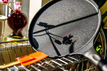 Fototapeta na wymiar black pancake smile frying pan on plate drainer rack in kitchen